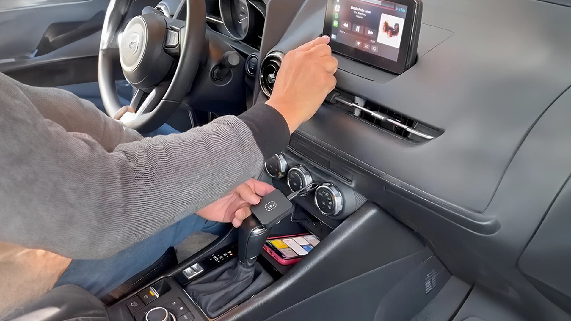 Driver interacting with a CarPlay system in a vehicle's dashboard, showcasing the ease of accessing car multimedia features